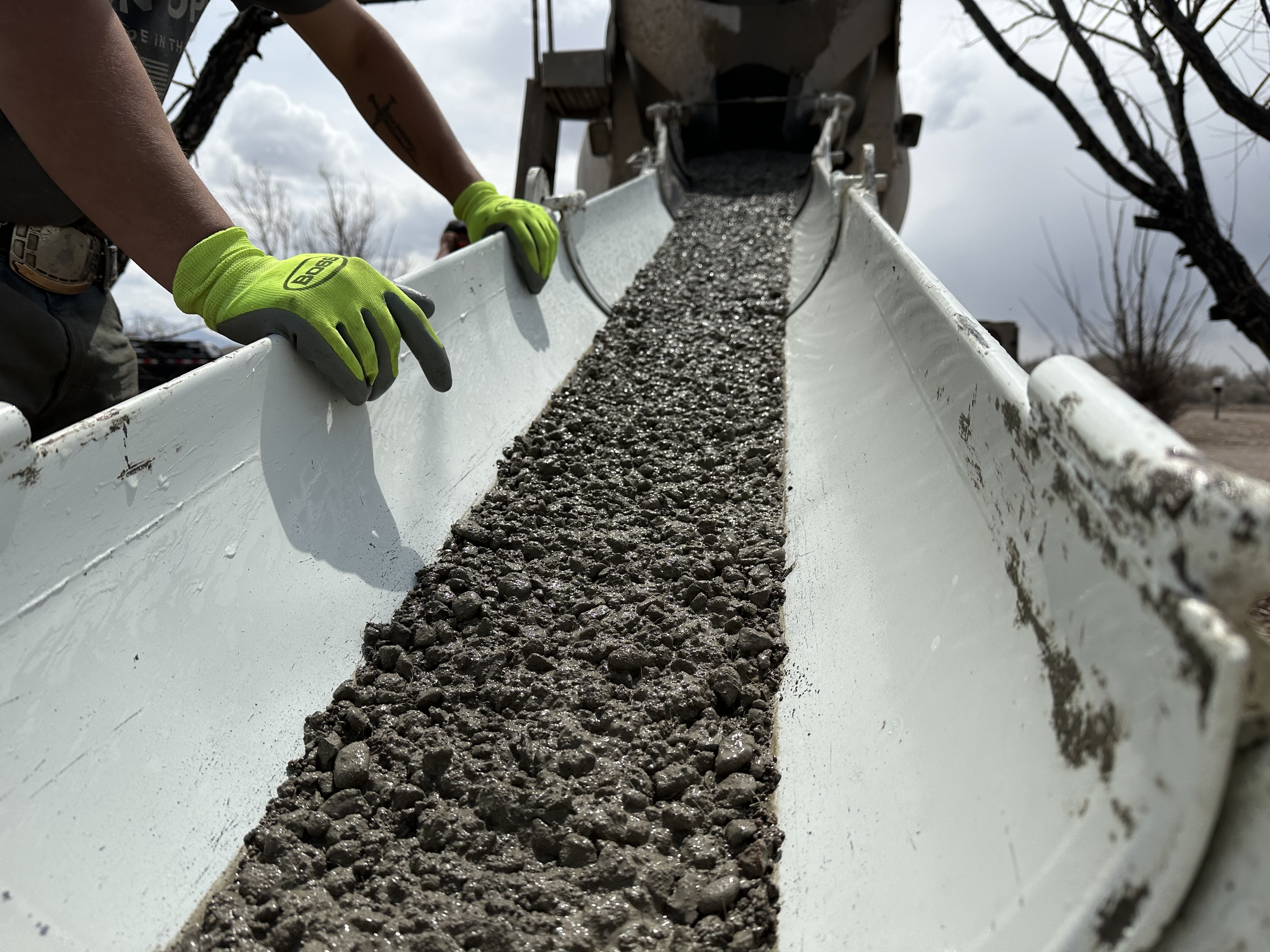 Concrete flowing down a chute from a mixer truck on a job site in Center, Colorado