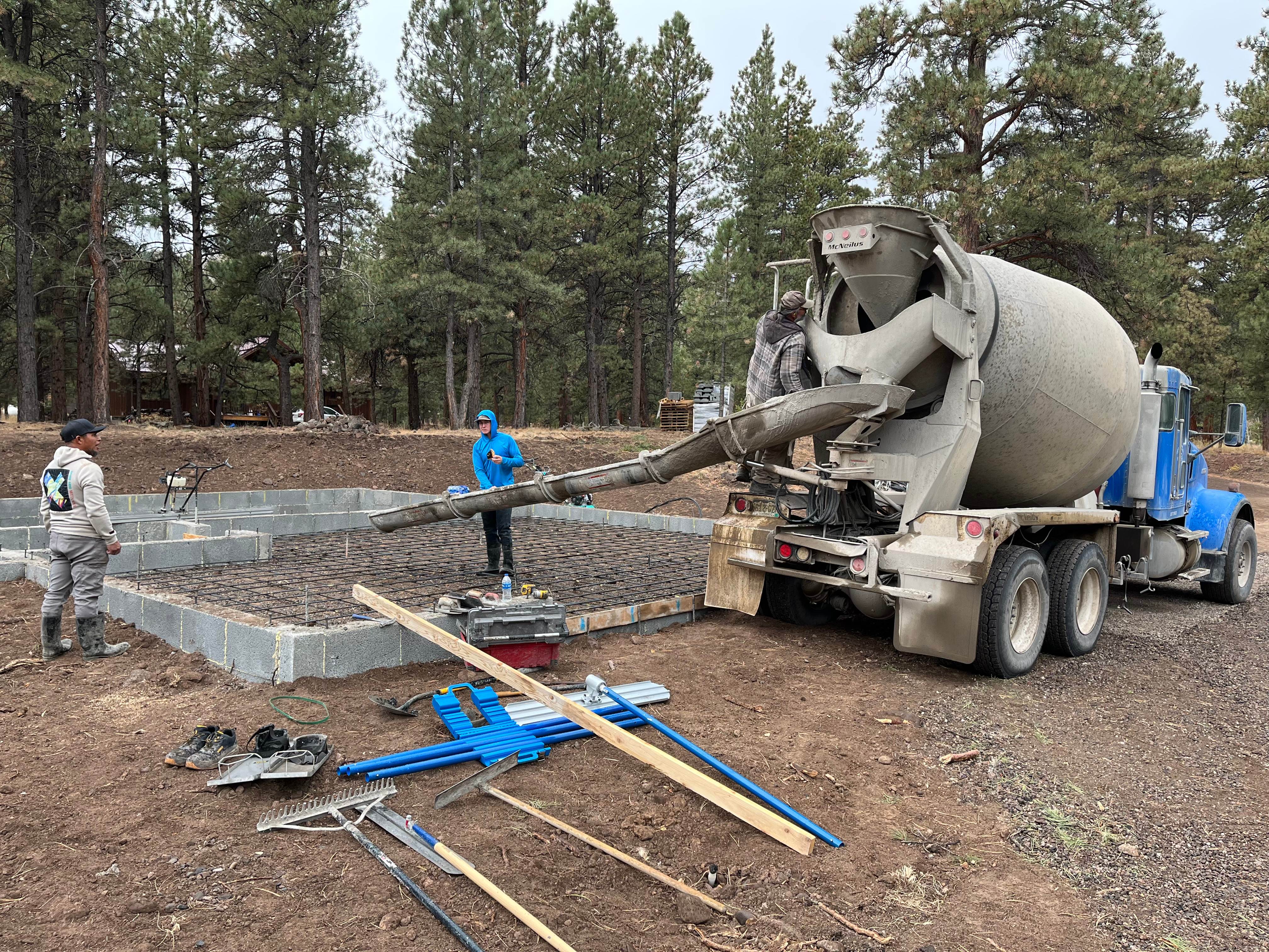 Foundation pour with rebar grid surrounded by pine trees